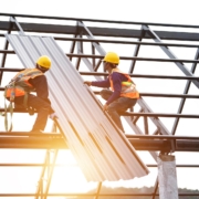 Workers replacing commercial metal roof panels