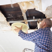 Person holding bucket above leak from roof